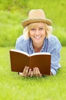 ung kvinna på en gräs med en bok foto