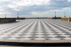 livorno, Italien-november 27, 2022-människor promenader på de mascagni terrass, en utmärkt belvedere terrass med checkerboard asfalterad yta, livorno, Toscana, Italien under en solig dag. foto