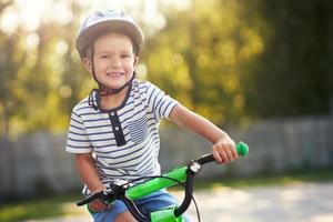 Lycklig 3 år gammal pojke har roligt ridning en cykel foto