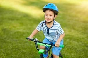 Lycklig 3 år gammal pojke har roligt ridning en cykel foto