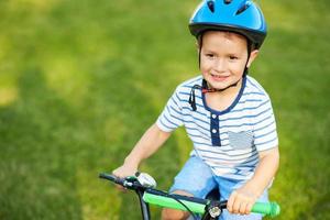 Lycklig 3 år gammal pojke har roligt ridning en cykel foto