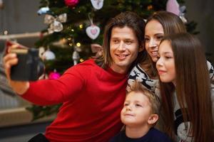 skön familj fira jul på Hem och tar omedelbar bilder foto