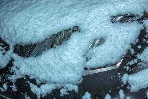 de frysta strålkastare av en bil är täckt med is och snö på en vinter- dag. stänga upp se. foto