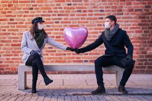 Lycklig par fira valentines dag i masker under covid-19 pandemi foto