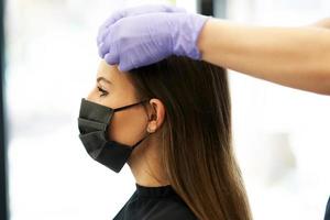 vuxen kvinna på frisör bär skyddande mask på grund av till coronavirus pandemi foto