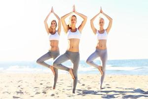 grupp av kvinnor praktiserande yoga på de strand foto