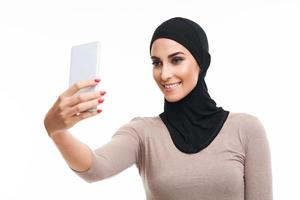 muslim kvinna använder sig av smartphone över vit bakgrund foto