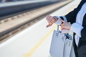 elegant kvinna gående med väska och resväska i de järnväg station foto