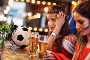 grupp av vänner tittar på fotboll i pub foto