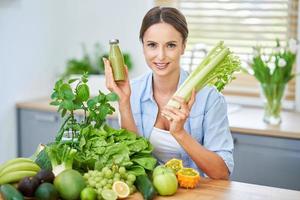 friska vuxen kvinna med grön mat i de kök foto