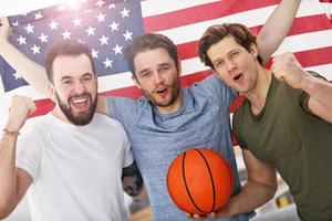 Lycklig amerikan basketboll fläktar glädjande över flagga foto