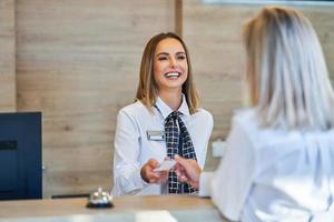 receptionist och affärskvinna på hotell främre skrivbord foto