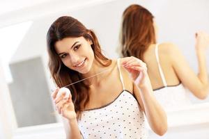 ung kvinna använder sig av dental flock i badrum foto