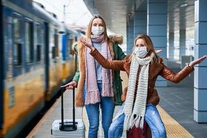 två kvinnor på tåg station bär masker på grund av till covid-19 restriktioner foto
