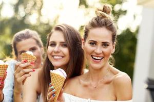 Lycklig grupp av vänner äter glass utomhus foto