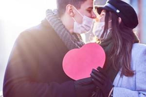 Lycklig par fira valentines dag i masker under covid-19 pandemi foto