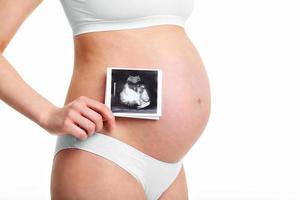närbild av gravid kvinna som håller ultraljudsundersökning på magen foto