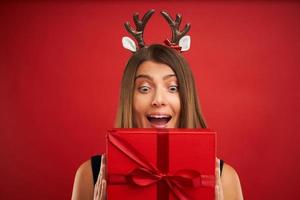 vuxen Lycklig kvinna med jul gåva över röd bakgrund foto