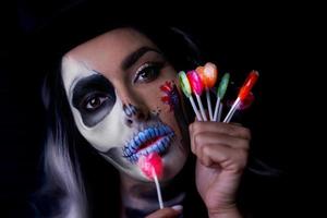 läskigt porträtt av kvinna i halloween gotisk smink innehav syllipops foto
