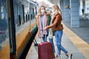 två kvinnor på tåg station bär masker på grund av till covid-19 restriktioner foto