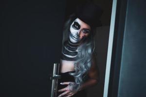 läskigt porträtt av kvinna i halloween gotisk smink öppning dörr foto