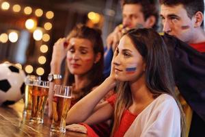 grupp av vänner tittar på fotboll i pub foto