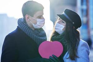 Lycklig par fira valentines dag i masker under covid-19 pandemi foto