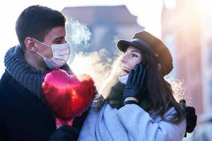 Lycklig par fira valentines dag i masker under covid-19 pandemi foto