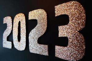 Lycklig ny år 2023. gyllene tal på en svart bakgrund med glitter foto