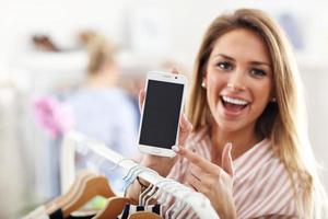 Lycklig kvinna i kläder affär innehav smartphone foto