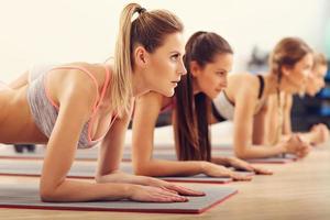 grupp av ung kvinnor håller på med planka tillsammans i Gym foto