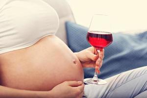 stänga upp av gravid kvinna med glas av vin foto