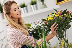 kvinna blomsterhandlare arbetssätt i blomma affär foto