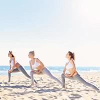 grupp av kvinnor praktiserande yoga på de strand foto