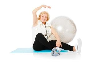 senior kvinna håller på med stretching övning på matta foto