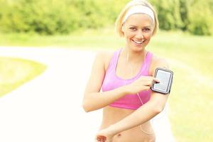 Lycklig joggare använder sig av en smartphone foto