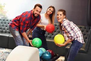 grupp av vänner spelar bowling foto