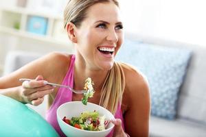 ung kvinna äter friska sallad efter träna foto