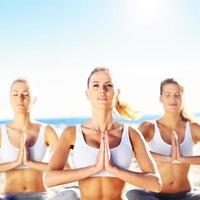 grupp av kvinnor praktiserande yoga på de strand foto