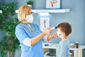 barnläkare läkare granskning liten barn i klinik temperatur kolla upp foto