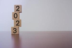 Lycklig ny år 2023. ny år bakgrund begrepp på trä- block. placerad på en trä- tabell. foto