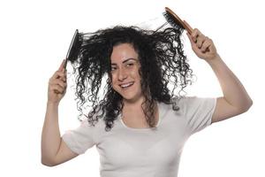 skön kvinna med hårkam fastnat i lockigt hår foto