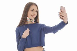 skönhet rolig Tonårs flicka framställning selfie med henne mobiltelefon foto