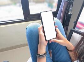 närbild av en kvinna hand innehav en smartphone vit skärm är tom .mockup. foto