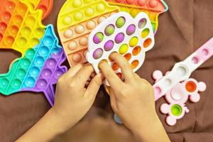 pop- den är en flerfärgad anti-stress leksak i barns händer. bubbla spel. antistress leksaker. foto
