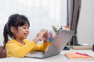 först dag på skola. asiatisk liten flicka använder sig av en bärbar dator dator, studerar genom uppkopplad e-learning systemet. foto