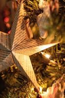 en papper stjärna prydnad hängande på en jul träd med mjuk lampor foto