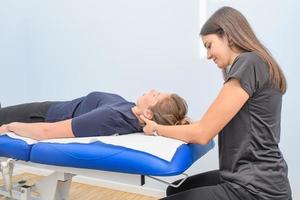 en fysisk terapeut behandlar en patientens nacke och cervical foto