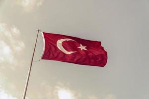 Turkiet flagga vajar i den blå himlen. foto