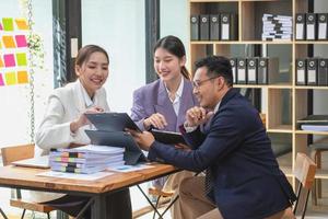 asiatisk företag team består av marknadsföring personal. revisor och finansiell officer hjälp varje Övrig analysera företag vinster använder sig av tabletter. kalkylator bärbar dator datorer, Graf papper, och företags- pennor. foto